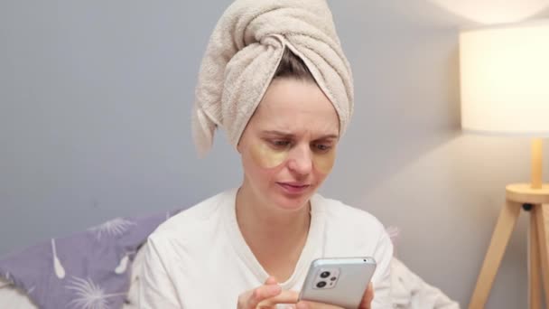 Shocked Surprised Woman Wrapped Towel Using Mobile Phone While Sitting — Stock Video