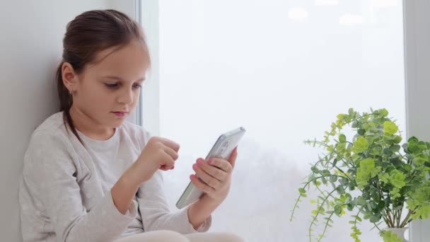 Urocza Brązowe Włosy Dziewczynka Relaks Parapecie Pomocą Telefonu Komórkowego Przewijania — Wideo stockowe