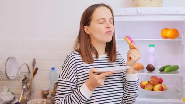Elégedett Eszik Egészségtelen Élelmiszer Közelében Hűtőszekrény Otthon Gazdaság Tányér Fánk — Stock videók