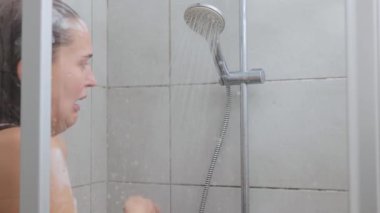 Kafkasyalı çıplak bir kadın soğuk duş alırken tepkimeye girdi. Dondurucu sudan yüzünü buruşturdu. Sabah hijyen rutini sırasında kafasında köpükle bekledi.