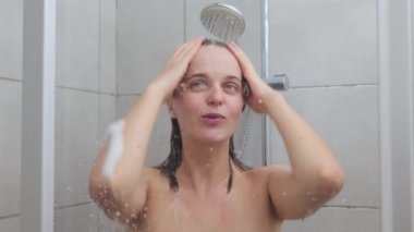 Cilt bakımı kozmetik sabah rutin prosedürleri. Yarı çıplak genç kadın duş alıyor şarkı söyleyerek uyanıyor keyifli bir şekilde duş alıyor ve saçlarını yıkıyor.