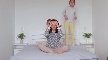 Evde yatağında oturan sinirli anne yatak odasında rahat bir şekilde koşuşturan yaramaz çocuklar yüzünden baş ağrısı çekiyor. Yoga yaparak sakinleşmeye çalışıyor.