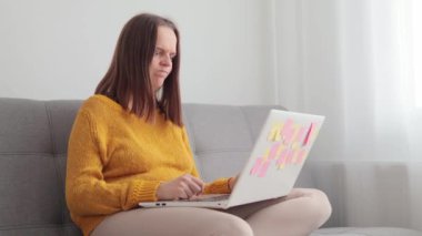 Kızgın, agresif, yorgun bir kadın evdeki kanepede oturup dizüstü bilgisayarda çalışıyor. Günlük kıyafetlerini giyiyor. Öfkeyle bağırıyor, internet bağlantısı veya yazılımla ilgili sorunları var.