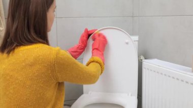 Kahverengi saçlı, eldiven giyen, ev banyosunda dezenfekte eden ev işleri yapan, banyo temizleyen bir kadın.