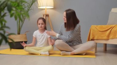 Spor ve oyun zamanı. Çocuklar için sağlık pratiği. Aktif oyun ve sağlık. Kafkasyalı kadın ve sevimli küçük kızı birlikte yoga yapıyorlar. Annesi çocuğa spor egzersizleri yapmayı öğretiyor.
