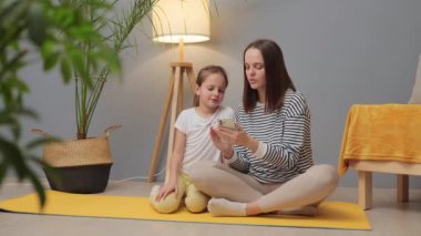 Birlikte ev egzersizi yapalım. Çocuğun aktif yaşam tarzı. Aile sağlığı ve bakımı. Annemin yoga eğitimi. Genç anne ve küçük kızı evde fiziksel antrenman yapıyorlar.