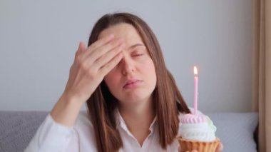 Hasta, sağlıksız bir kadın doğum gününü pastayla kutlarken grip belirtileri gösteriyor hapşırıyor ve lezzetli tatlı üzerine yanan mum üflüyor.