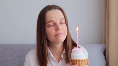 Mutsuz, hayal kırıklığına uğramış, kahverengi saçlı, kanepede oturan, olumsuz duygularını ifade eden, yalnız ve stresli bir bayramı kutlayan, mutsuz bir kadın.