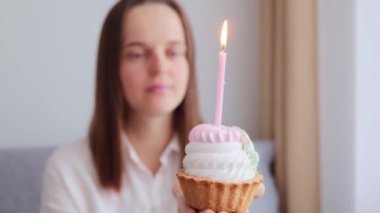 Lezzetli pastanın kapanışı. Arka planda bulanık bir kadınla yanan pasta. Kahverengi saçlı kadın doğum gününü kutluyor.