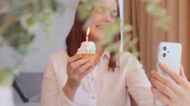 Neşeli kahverengi saçlı kadın doğum gününü videoda kutluyor. Doğum günü şarkısını söylüyor. Mutlu yıllar şarkısını söylüyor.