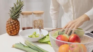 Tanınmayan bir kadın mutfak masasında taze kabak ve avokado tutuyor. Salata için taze sebzelerle dolu. Evde organik yiyecekler hazırlıyor.