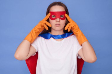 Hasta, beyaz saçlı, süper kahraman kostümü giyen beyaz tişört giyen, mavi arka planda izole edilmiş lastik eldivenli, hasta, beyaz saçlı kadın.