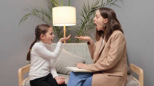 清晰的修正程序 儿科语言专家 为演讲提供教育支持 深色头发的教师语言治疗师坐在沙发上和小女孩练习发音练习 — 图库视频影像
