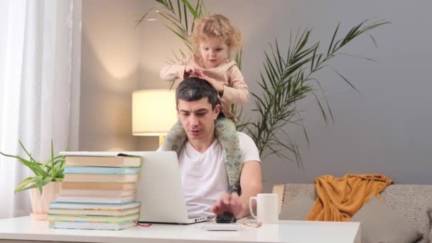 ベイビーとリモートワーク ビジネスと親として 子どもの仕事に対する影響 自宅で肩に赤ちゃんの娘とラップトップで作業している混乱した白人男性 — ストック動画