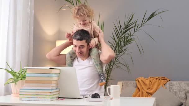 创业爸爸 平衡工作与儿童的关系 家长在线学习 在笔记本电脑上工作的白人男子 肩上背着小女儿在家里 — 图库视频影像
