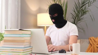 Kar maskesi giymiş, laptopunu kullanan, kendini rahat hisseden, tehlikeli işlerinde rahat hisseden, kahve içen, özel bilgilerini çalan tanınmamış bir adam.