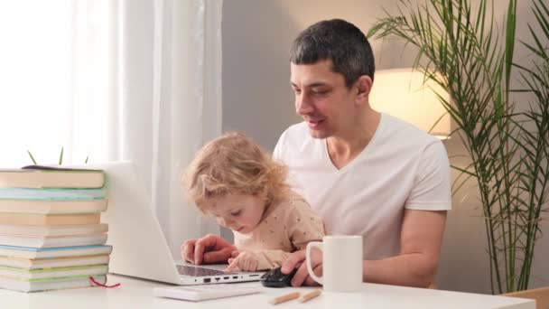 心满意足的男人穿着休闲装 穿着T恤在笔记本电脑上与蹒跚学步的男婴父亲一起工作 享受自由自在的生活 并有很多时间和他年幼的女儿一起坐在家里的餐桌旁 — 图库视频影像