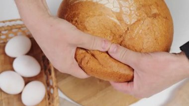 Lezzetli yemek için bir somun ekmek. Tanımlanamayan kadın fırıncı elleri masada tam tahıllı ekmek kırıyor.