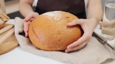 Tahta bir masada taze ekmek. Organik fırın ürünlerine yakın çekim. Mutfakta tam buğday ekmeği. Ev yapımı ekmek hazırlığı. Geleneksel bir somunun lezzetli kabuğu..