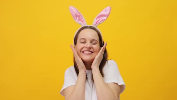 イースターのお祭りと楽しい 春のイベントを祝う うさぎを身に着けている白人女性 幸せに笑顔で立っている黄色い背景の上に隔離されたヘッドバンド — ストック動画