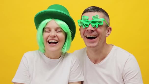 非常に幸せな女性 緑の髪とクローバーの帽子と男性 イエローバックグラウンドに隔離され 大声で大声でセントパトリックの日を祝う肯定的な感情を表現 — ストック動画