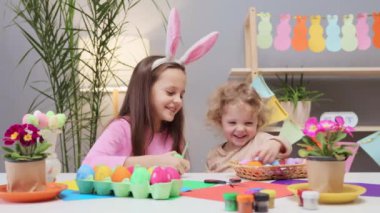 Paskalya yumurtası boyama partisi. Dağınık yumurta boyama eğlencesi. Paskalya için yumurta süsle. Çocuklarla yumurta boyama. Küçük kızlar yumurtaları canlı renklerle dekore ediyorlar.