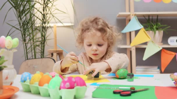 活性卵染色活動について イースターのお祝いに加えられた絵の卵 お祝いの家のインテリアでイースターエッグを描く小さな幼児少女 装飾プロセスを楽しむ面白い幼児の子供 — ストック動画
