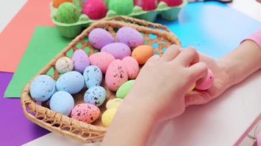 Renkli boyalı paskalya yumurtaları sepette tanınmaz halde küçük kız elleri dekore edilmiş yumurtalar alıyor güzel resimlere ve desenlere bakıyor.