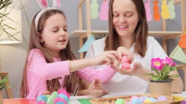 Çok mutlu bir aile birlikte vakit geçirirken masa başında oturup bayram hazırlıkları için şenlikli bir ortam yaratarak Paskalya yumurtaları boyuyor.