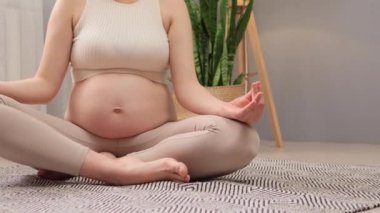 Hamilelik sırasında Lotus pozunda meditasyon yaparken evde sağlığıyla ve akıl sağlığıyla ilgilenen kimliği belirsiz hamile bir kadın yoga seansından zevk alıyor.