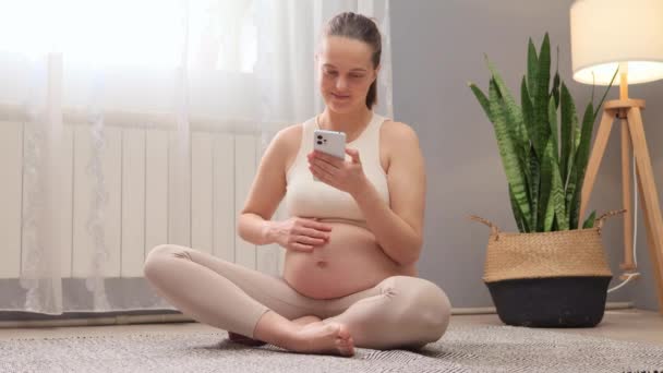 Mujer Embarazada Alegre Sosteniendo Teléfono Móvil Tocando Vientre Mientras Desplaza — Vídeos de Stock