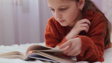 Koyu renk saçlı, kahverengi kazak giyen, kitap okuyan, sayfaları çeviren, ilginç romanlar ya da yatak odasındaki peri kuyruğuyla eğlenen bir kız.