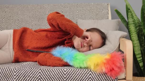 睡眠中の小さな少女は 家について働いて疲れた子供をこすってソファーに横たわった後 起き上がった茶色のセーターを着用し 疲れを感じます — ストック動画