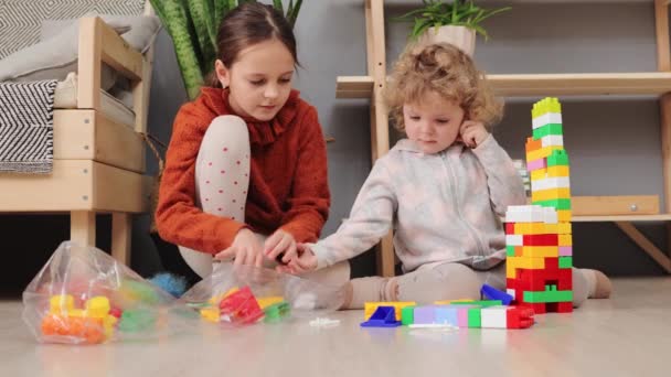 Маленькая Девочка Малышка Старшей Сестрой Играющая Красочными Блоками Конструкций Дома — стоковое видео