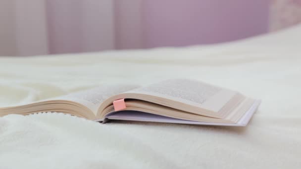 広告のための風のコピースペースが付いているページを回すベッドの上に横たわる開いた本 — ストック動画