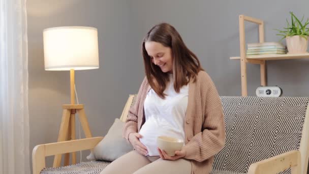 임신한 엄마를위한 신선한 어머니의 잔치를 기쁘게 소파에 과일을 그녀의 — 비디오
