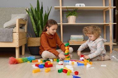 Oturma odasındaki bloklarla oynayan çocuklar, inşaatçılarla figürler yaparak ilginç oyunların keyfini çıkarıyorlar.