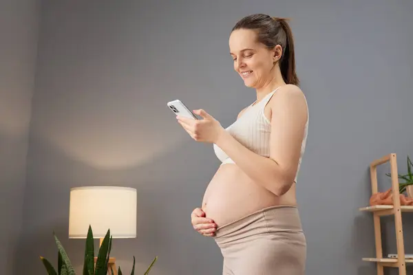 Expectant Mother Wearing Beige Attire Utilizing Her Smartphone Using Mobile — Stock Photo, Image