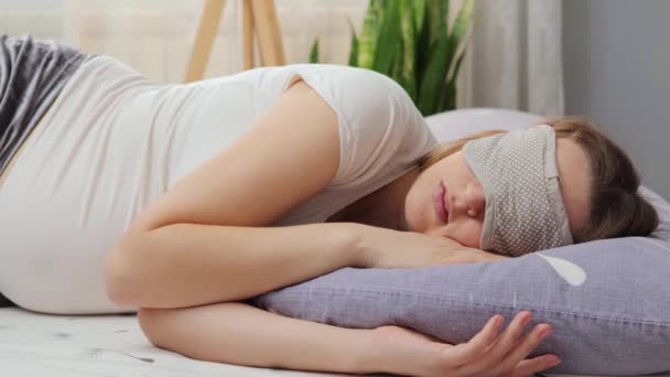 寝室のベッドで目隠しの眠りを身に着けている妊娠中の女性は 安らかにママに眠る瞬間を幸せに休ませて楽しんでいます — ストック動画
