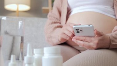 Tanımlanamayan sağlıksız hasta hamile kadın akıllı telefonu kontrol ediyor internetten internet sayfalarına bakıyor annelik tedavisi talimatlarını arıyor.