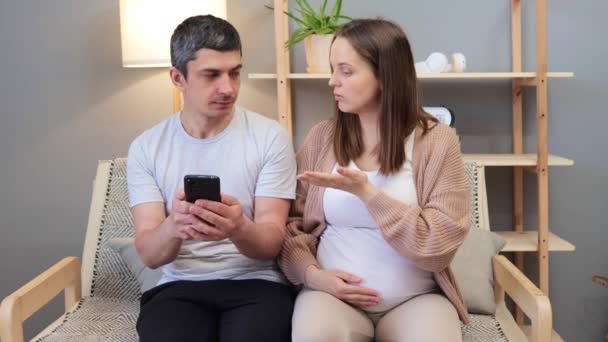 心烦意乱的白种人孕妇在心理咨询期间抱怨丈夫的智能手机成瘾 帮助夫妇解决电器过度使用问题 — 图库视频影像