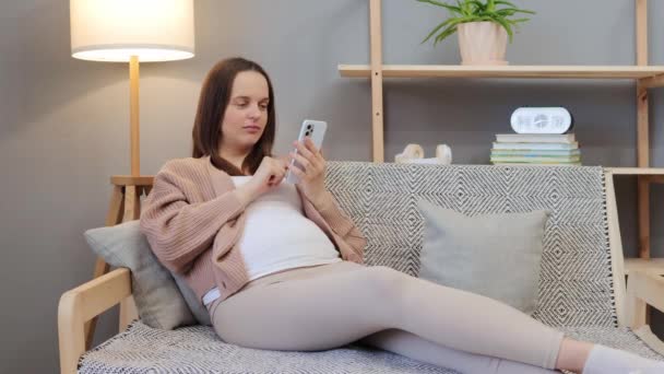 Zaniepokojona Kobieta Ciąży Rasy Kaukaskiej Bólu Kanapie Domu Pomocą Smartfona — Wideo stockowe