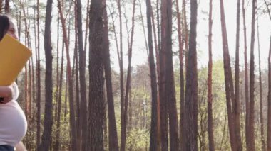 Kahverengi saçlı, göbek paspası olan, yoga antrenmanına hazırlanan ve aktif hamileliğinin tadını çıkaran neşeli, genç, beyaz bir kadın.