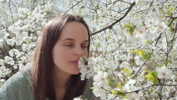 令人不快的棕色头发女人在花园里闻到樱花绽放后 因不愉快的感觉而面带笑容打喷嚏 — 图库视频影像
