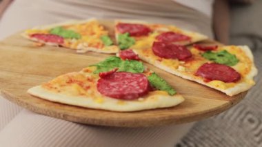 Hamilelik boyunca sağlıksız beslenme. Tanımlanamayan hamile bir kadının bacaklarındaki leziz peynirli pizzanın yakın çekimi.