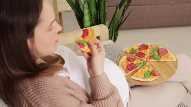 白种人孕妇一边吃着披萨 一边舒服地坐在沙发上 细细品味着每一口芝士味道鲜美的不健康营养 — 图库视频影像