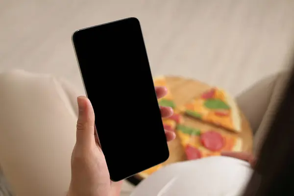 Unrecognizable Pregnant Female Eating Pizza Using Mobile Phone Holding Smartphone Stock Photo