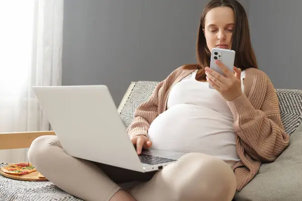 Caucasian Pregnant Woman Using Laptop Cellphone Resting Sofa Chatting Online Stock Photo