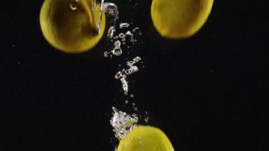 Taze limonlar suya atıldı ve siyah arka planda izole edildi.