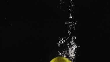 Sağlıklı yemek, diyet, tazelik. Taze limon meyveleri berrak suya sıçrıyor. Siyah arka planda izole edilmiş.